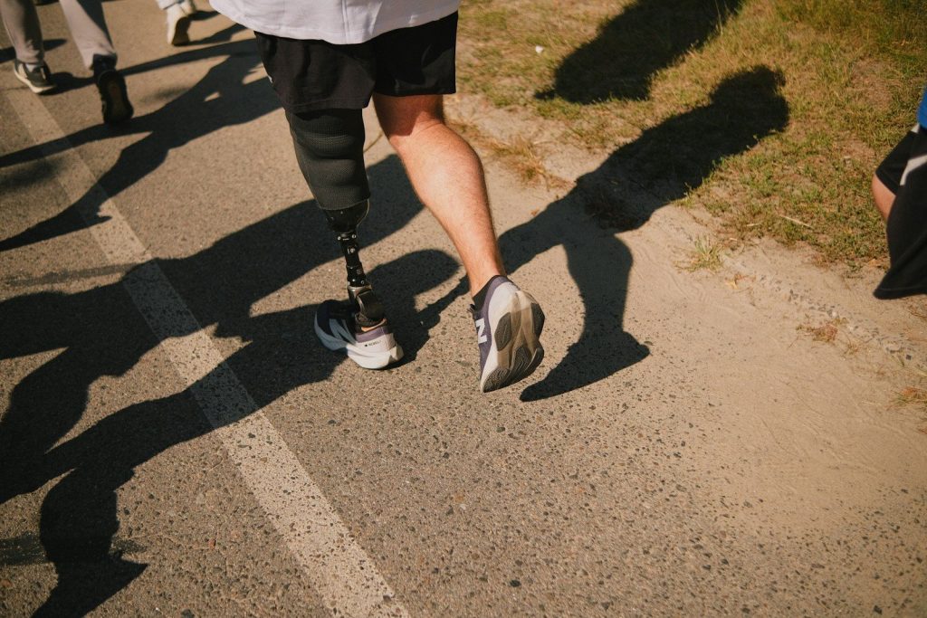 Runner with prosthetic leg racing on asphalt path
